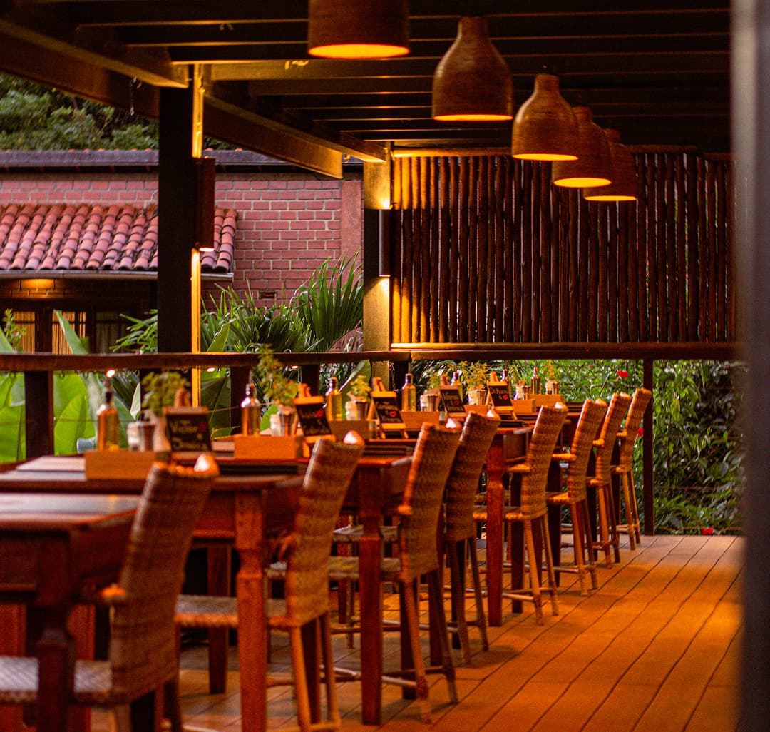 Salão do Restaurante do Vale ao entardecer com deck de madeira e jardim tropical em Fernando de Noronha